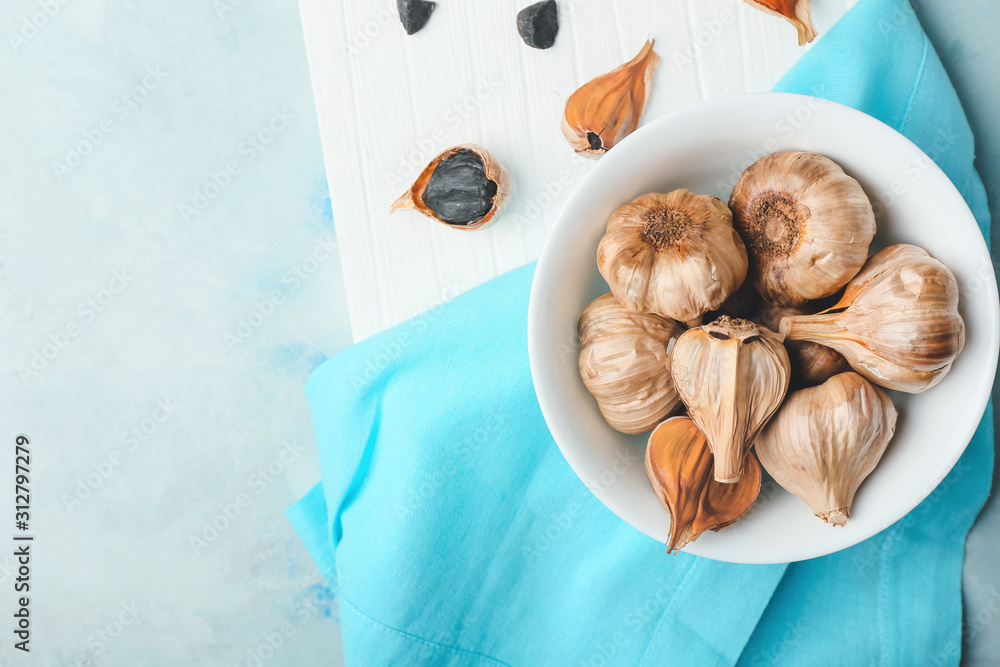 Bowl with black garlic on table