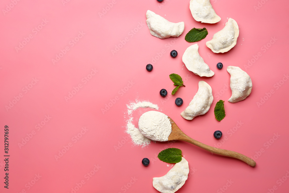 Raw dumplings with blueberries on color background