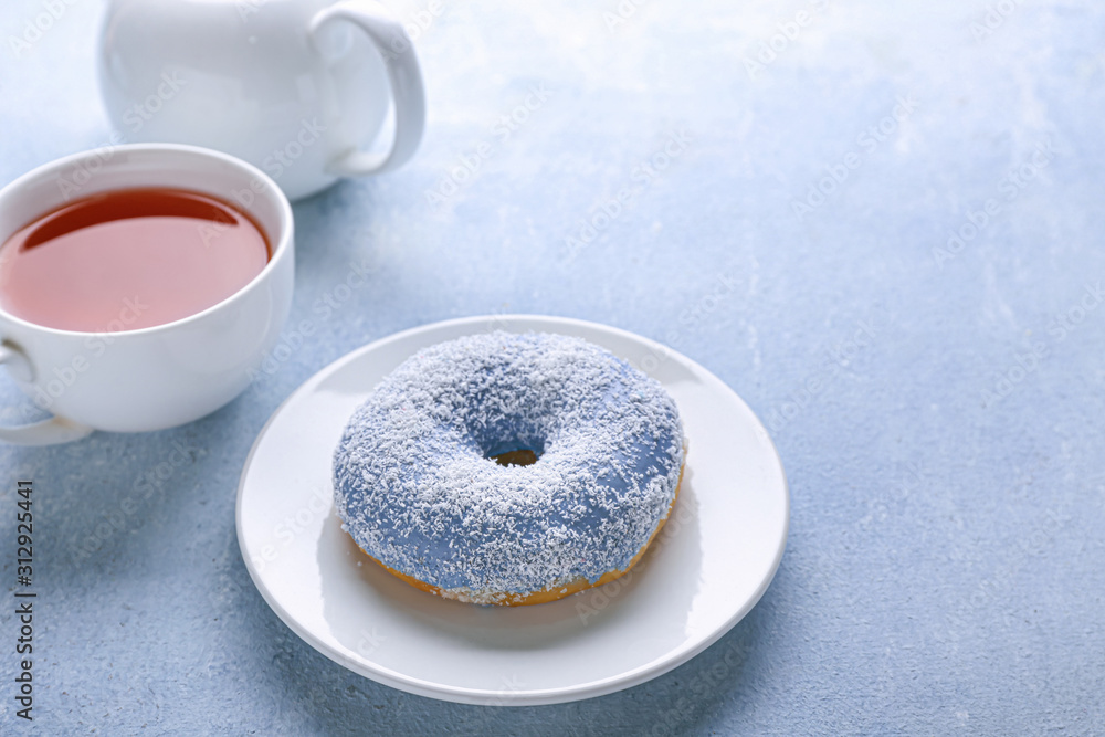 Plate with tasty donut and tea on color background