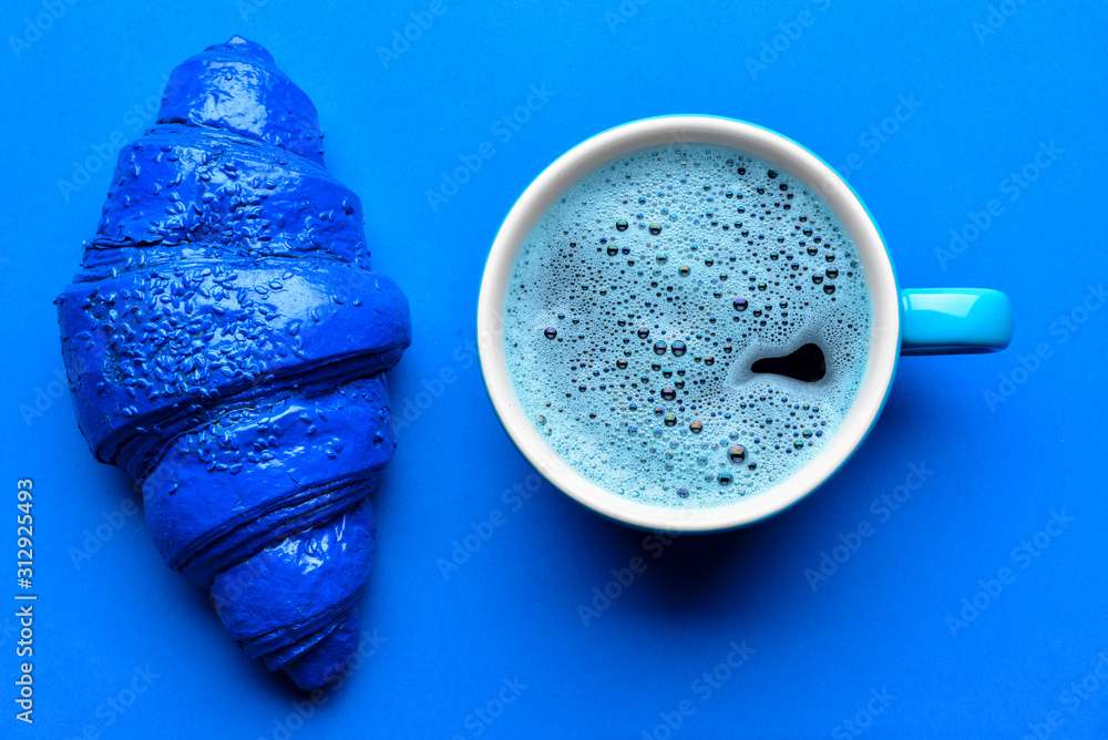 Blue croissant and cup of coffee on color background