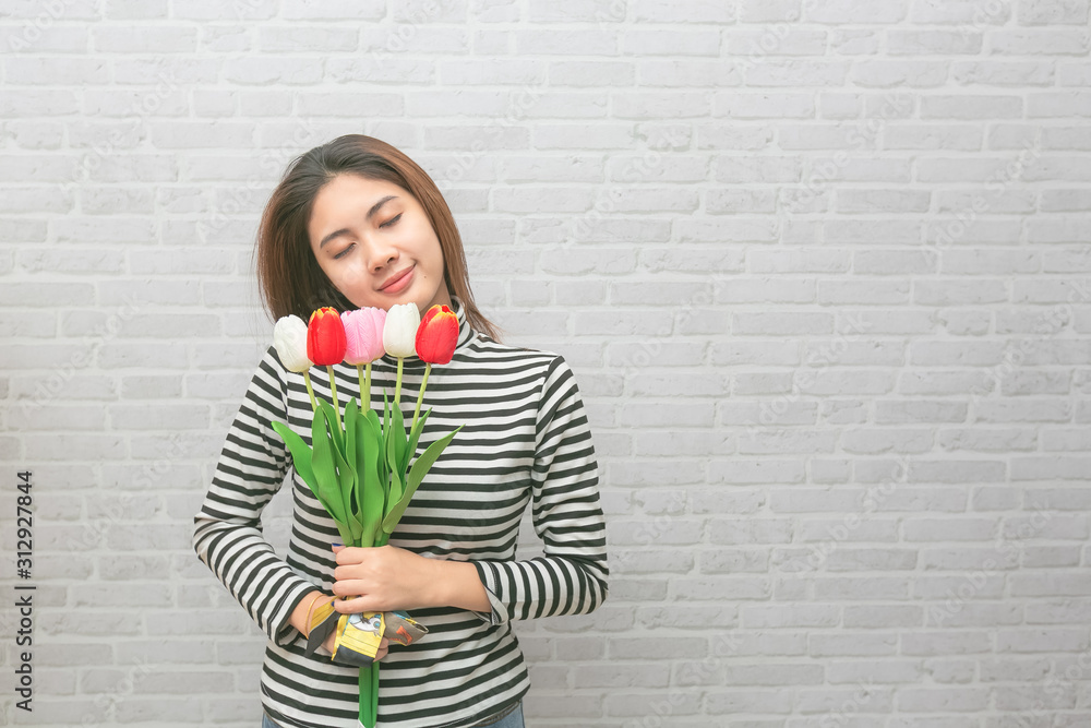 Beautiful womanl with flowers tulips in hands on a light background.