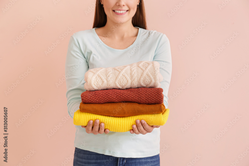 Young woman with clean laundry on color background