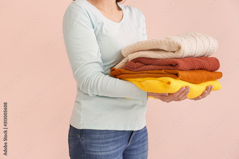 Young woman with clean laundry on color background