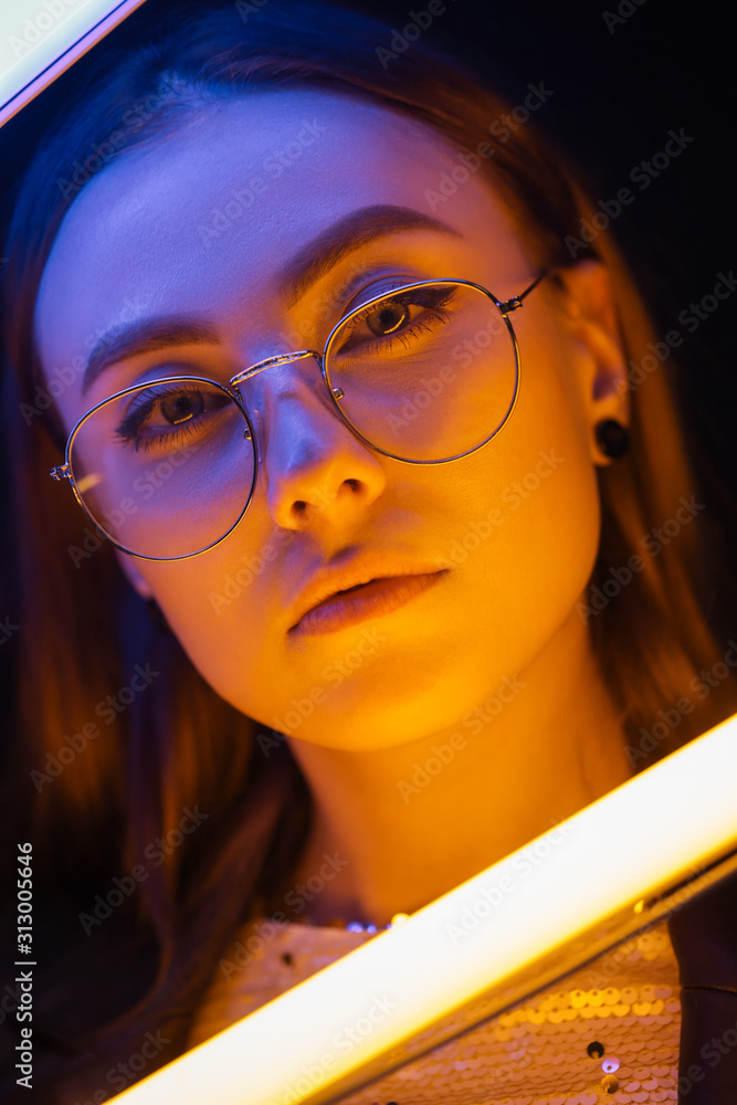 Toned portrait of beautiful woman with neon lamps on dark background