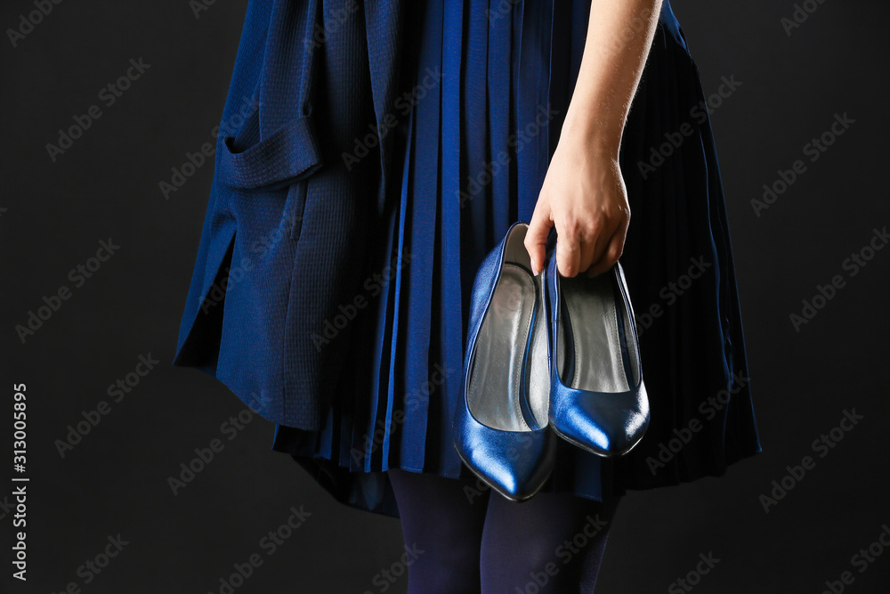 Young woman with blue high-heels on dark background, closeup