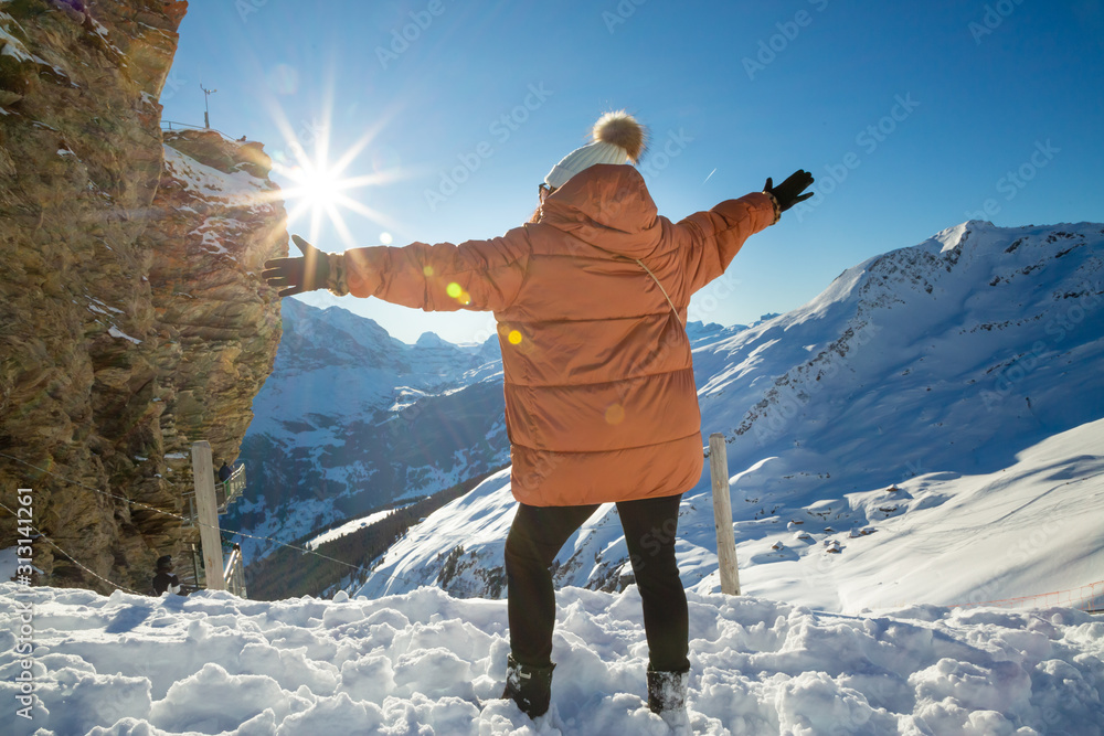 一张美丽的女人在度假时快乐地看着一座有很多雪的山的照片