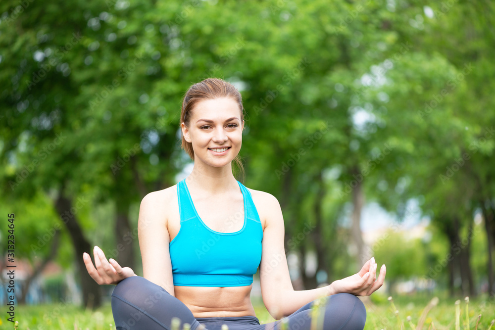 Girl meditates in lotus pose on green grass