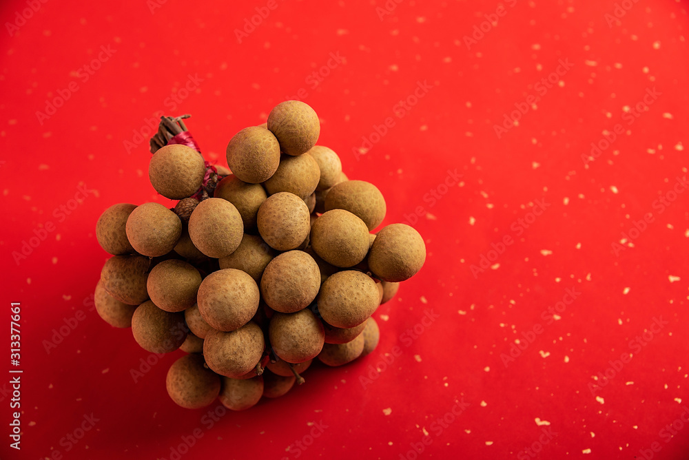 A handful of fresh fruit longan on red background