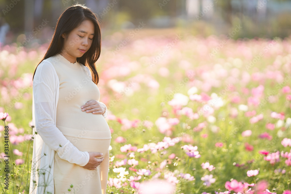 Pregnant woman is relaxing in the flower garden.