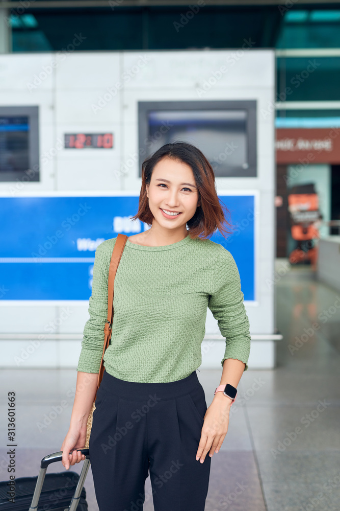 旅行。年轻女子带着行李箱在机场窗口等飞机