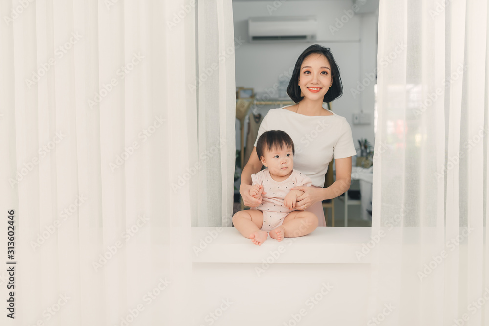 Mother and daughter sitting on sill near window