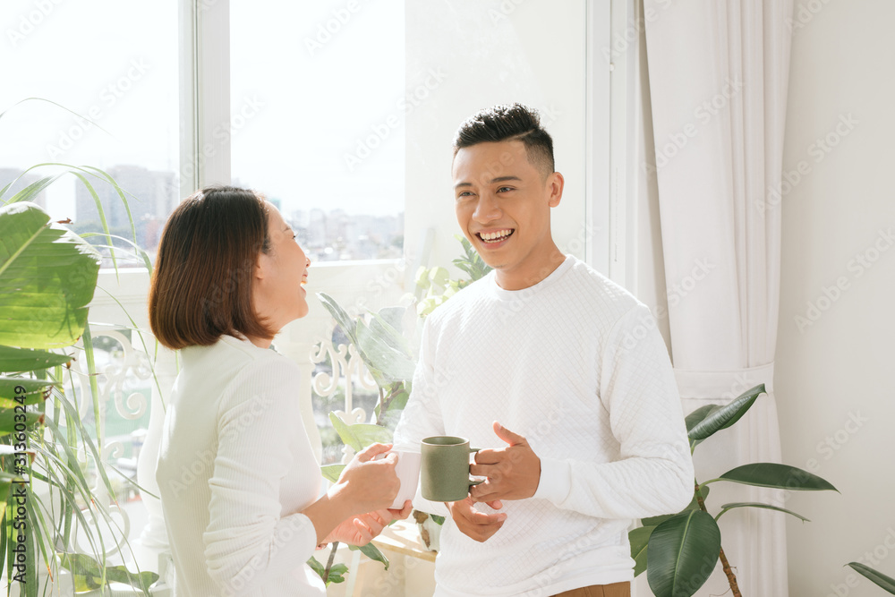 Young asian couple drinking coffee in living room at home