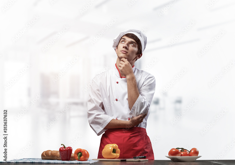 Young male chef standing with folded arms