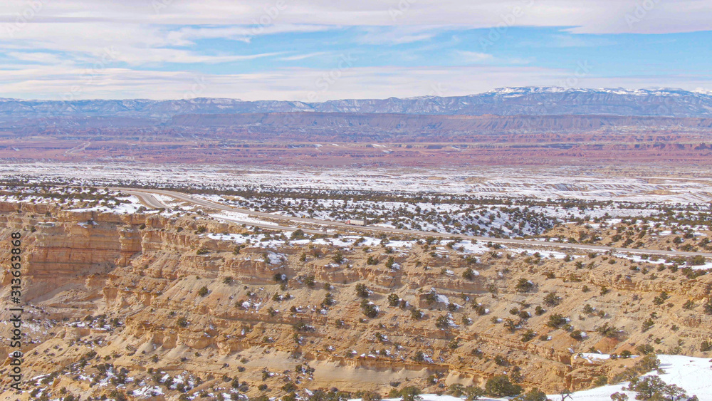 AERIAL: Freight truck drives down scenic highway running along side of a canyon