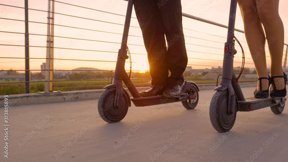 LENS FLARE: Co-workers in formal wear ride electric scooters to work at sunrise.