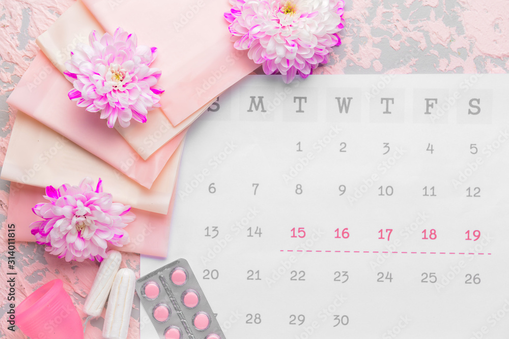 Menstrual calendar with feminine products and pills on color background