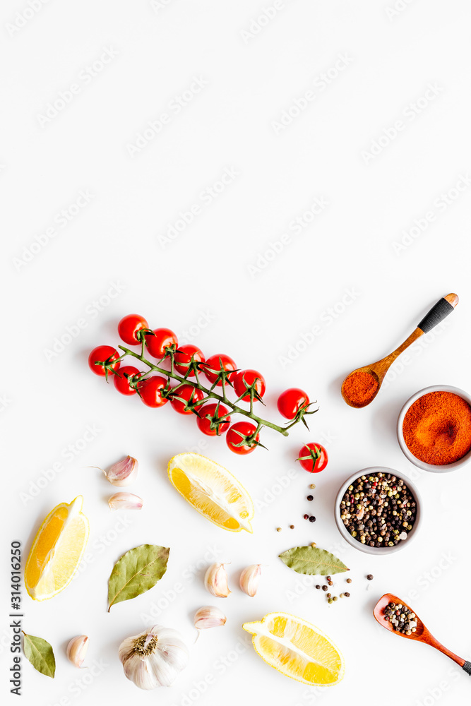 Cooking background with spices, vegetables - pepper, garlic, cherry tomatoes - on white desk top-dow