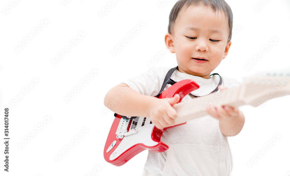 Happy little asian toddler boy sing a song and playing guitar on white background.