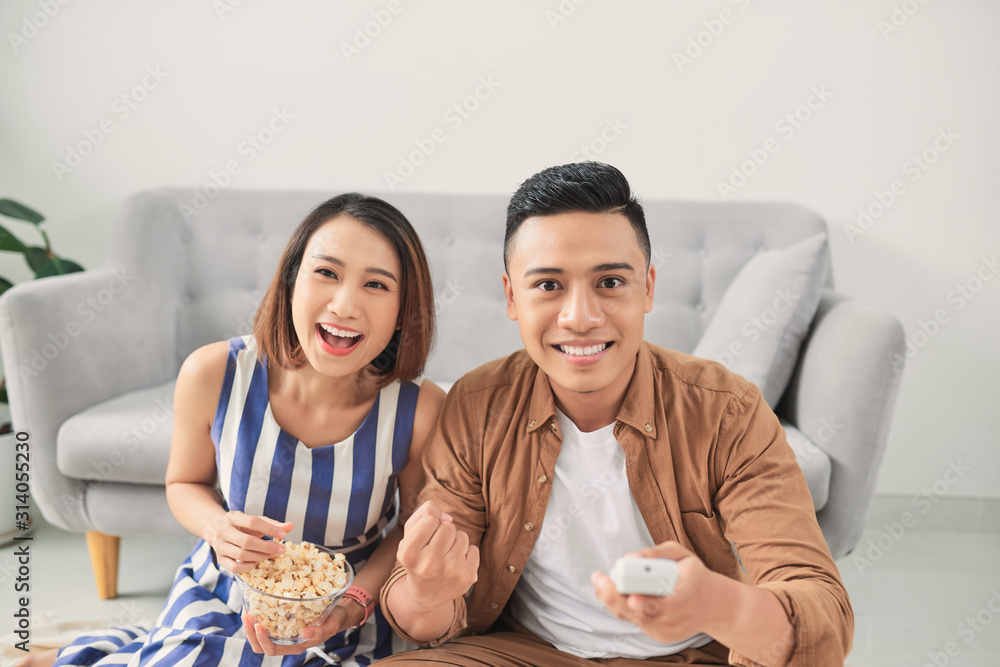 Happy young couple relaxing and watching TV at home.