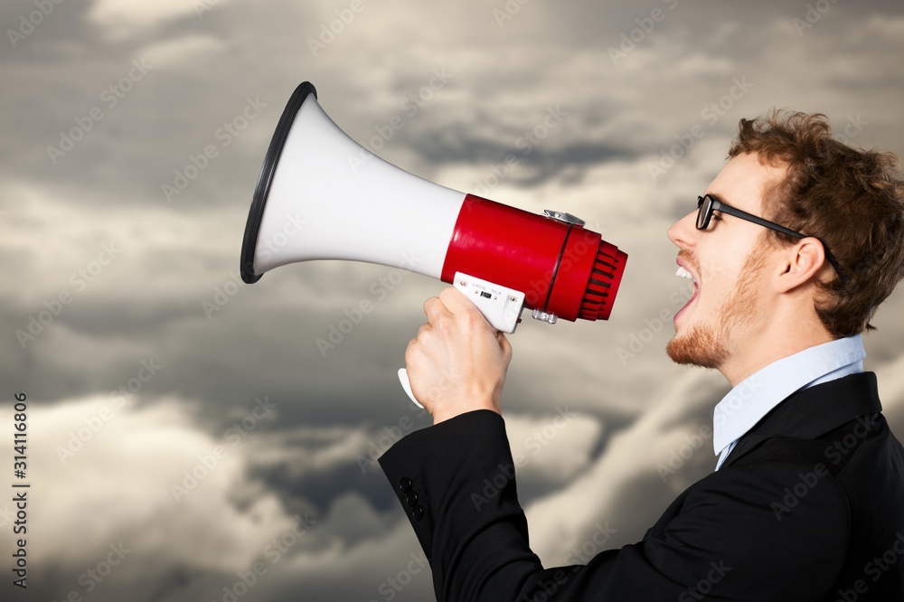 Angry man screaming in Megaphone on sky background