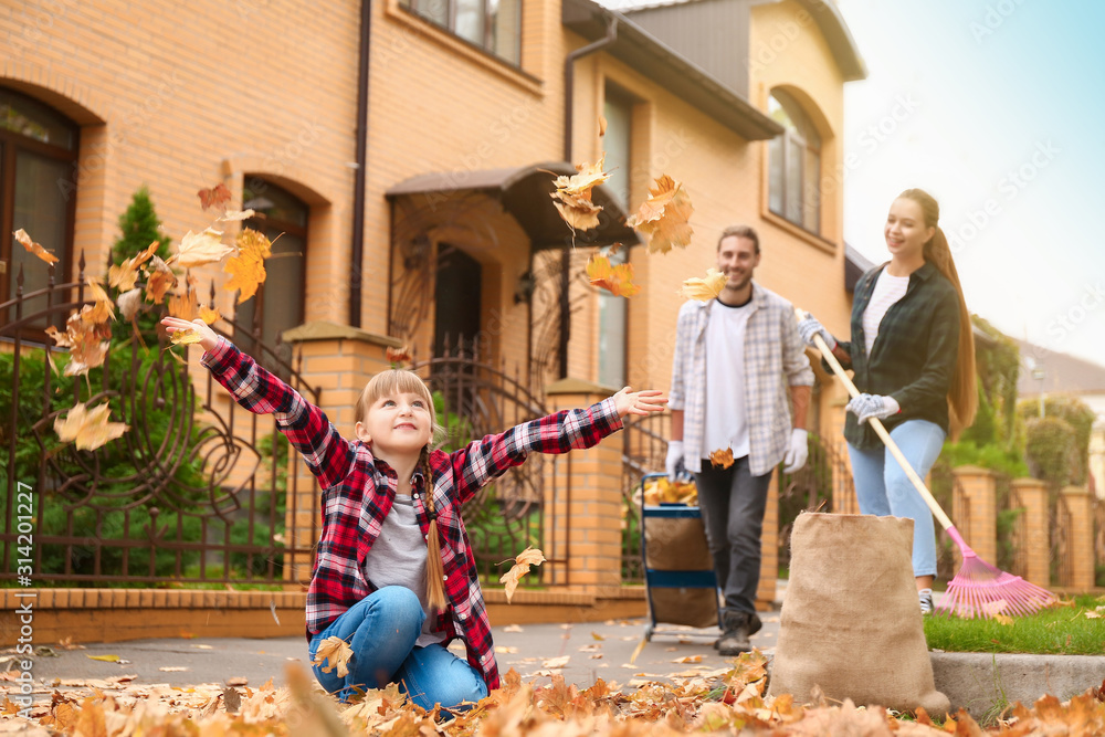 Family cleaning up autumn leaves outdoors