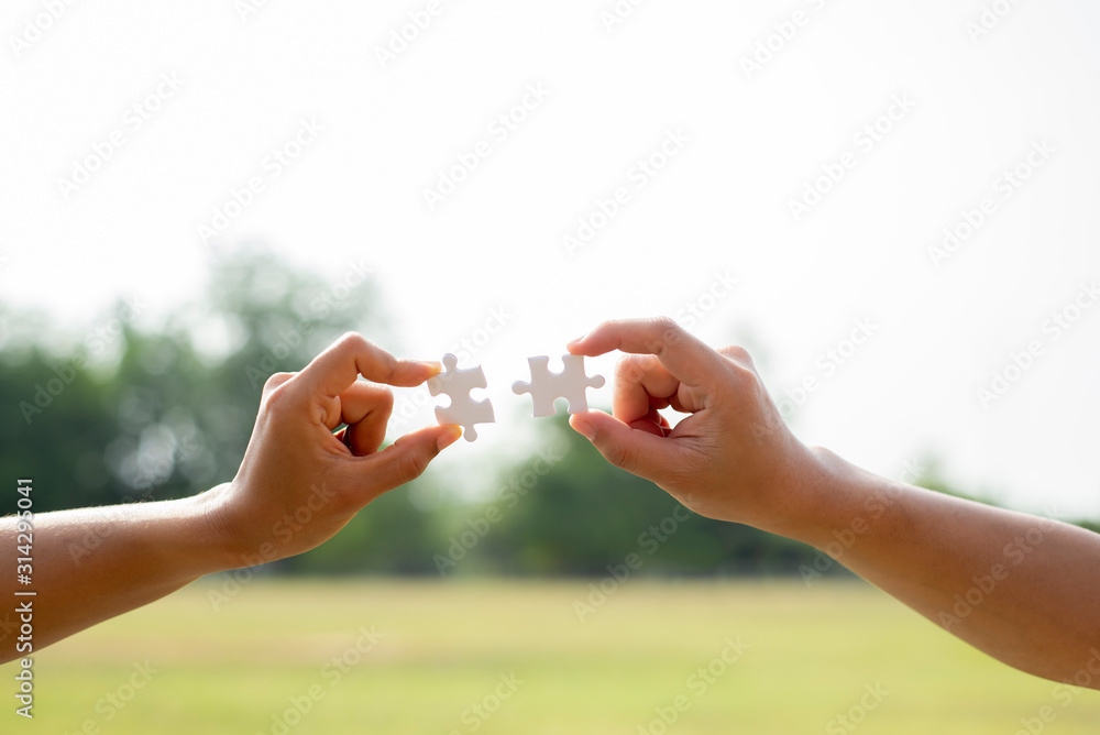 Closeup hand on  woman with  man  holding  puzzle jigsaw to sky connecting