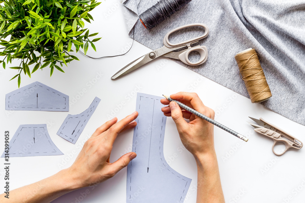 Tailor working. Women hands make patterns for clothes on white background top-down