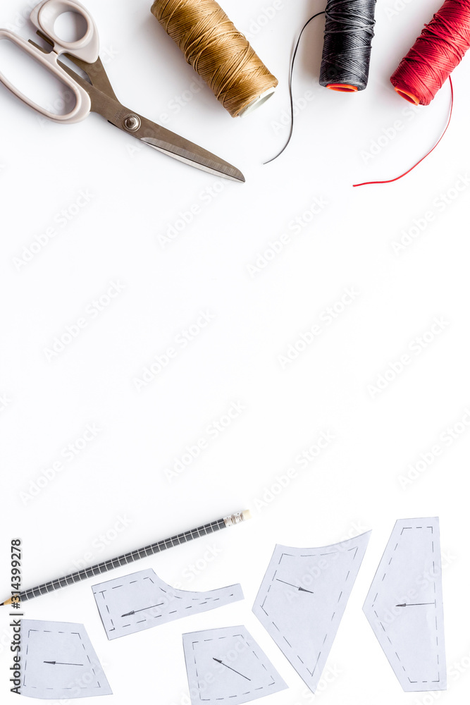 Clothes designer work desk. Pattern, scissors, thread on white background top-down copy space