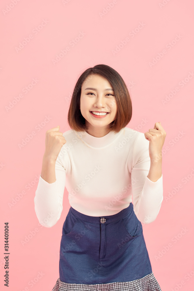 Portrait of an excited asian businesswoman looking at camera isolated over pink background