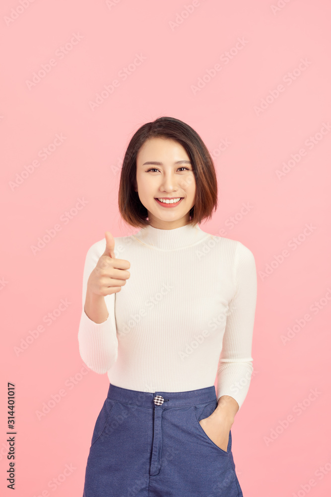 Young Asian woman show thumbs up on pink background