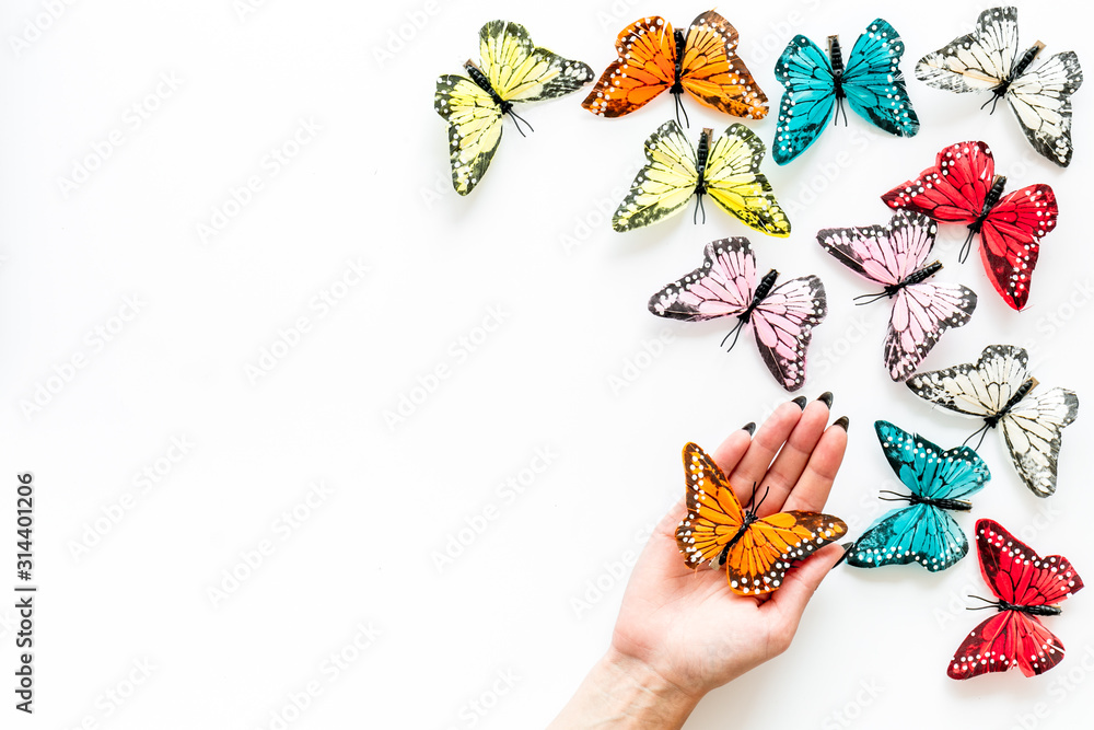 Butterfly on women hand near set of multicolored butterflies on white background top-down