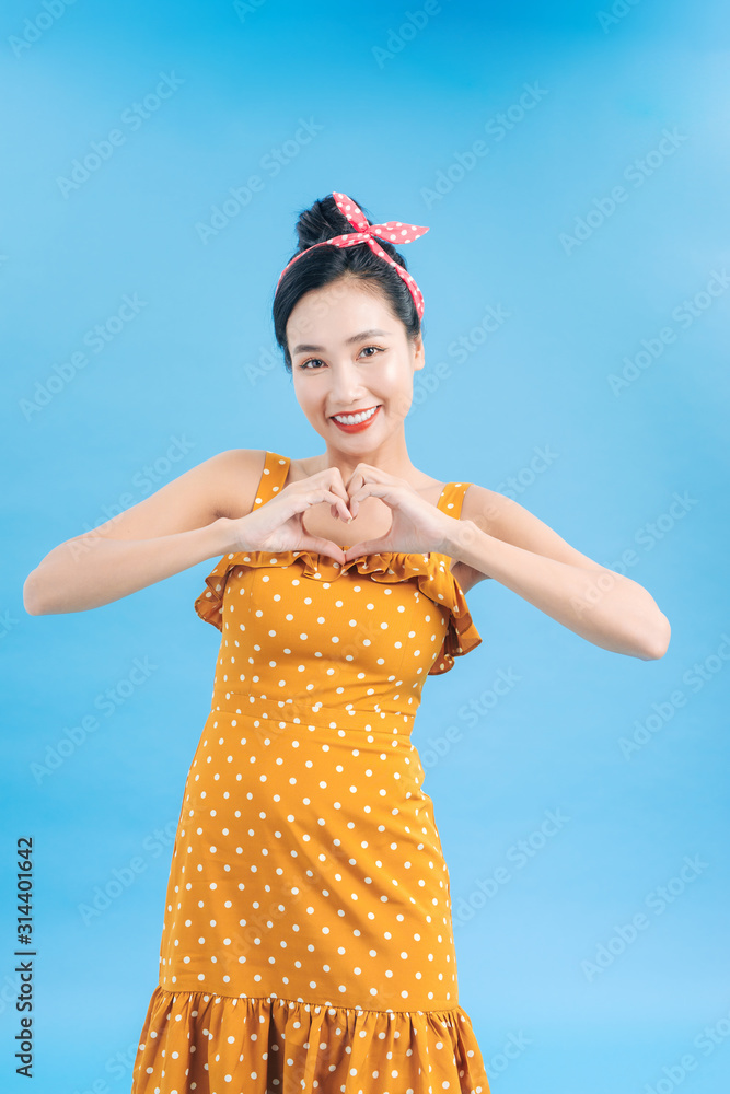 Love. Closeup portrait smiling happy pin up woman making heart sign symbol with hands isolated blue 