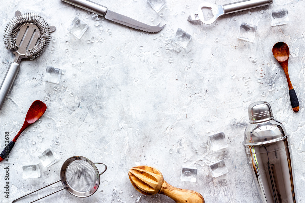 Bar utensil, tools - shaker, stainer - near ice cubes on grey background top-down frame copy space