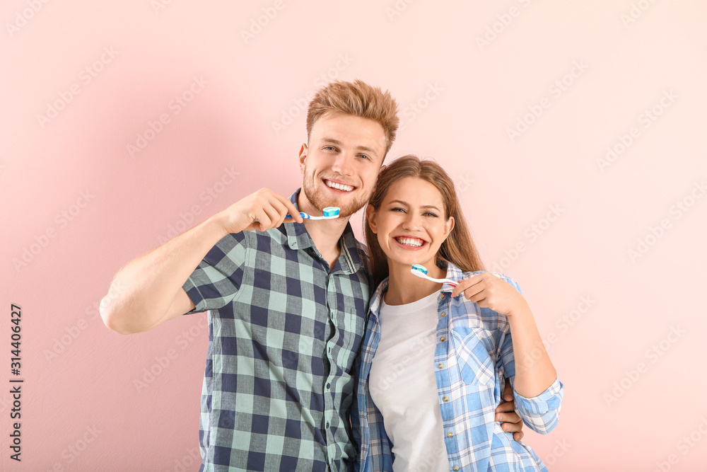 Young couple brushing teeth on color background