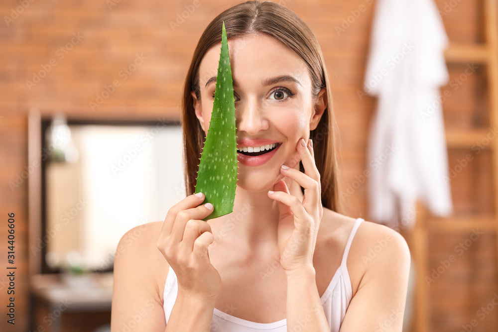 Beautiful young woman with aloe vera in bathroom