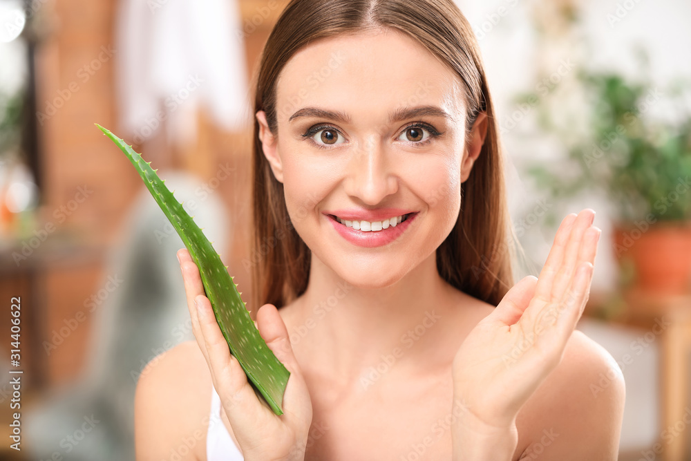 Beautiful young woman with aloe vera in bathroom