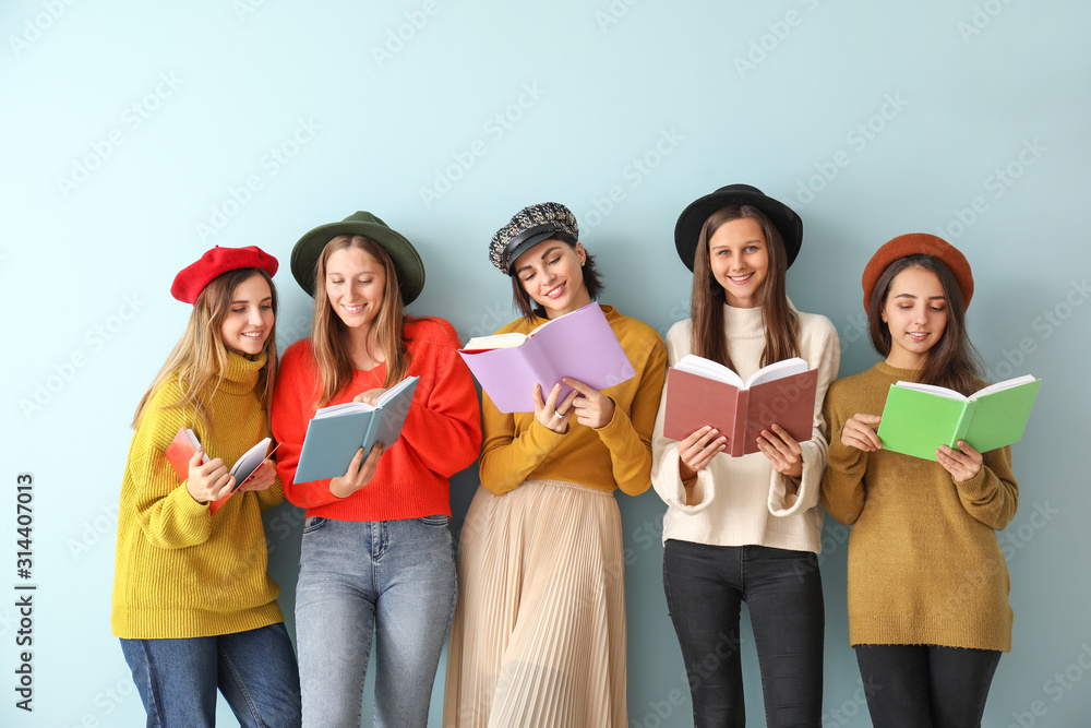 Young women with books on color background