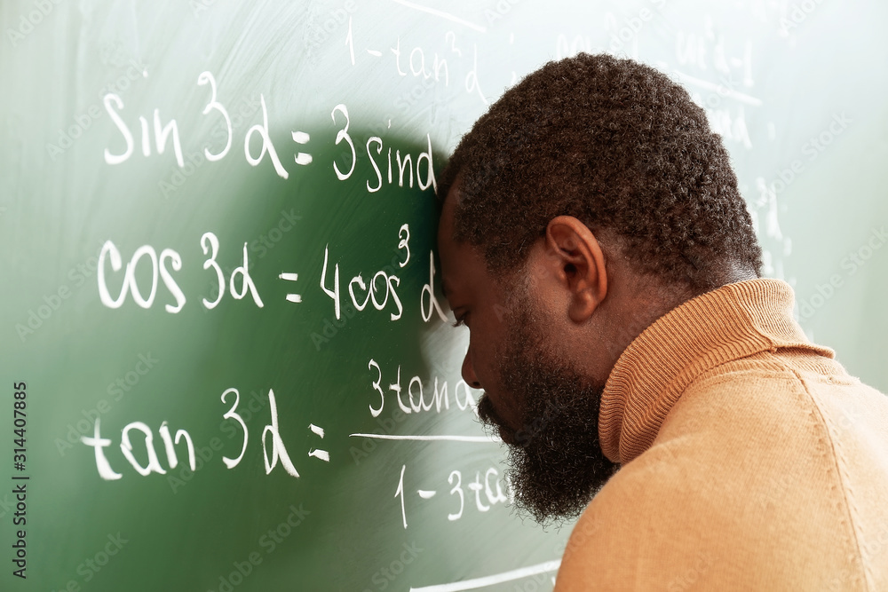 African-American math teacher in despair near blackboard