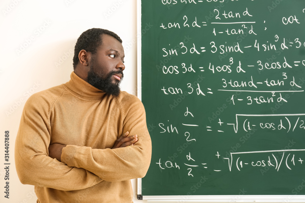 African-American math teacher near blackboard in classroom