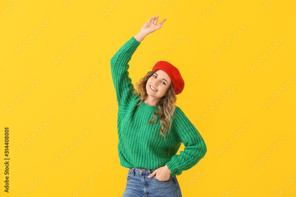 Beautiful young woman in warm sweater on color background