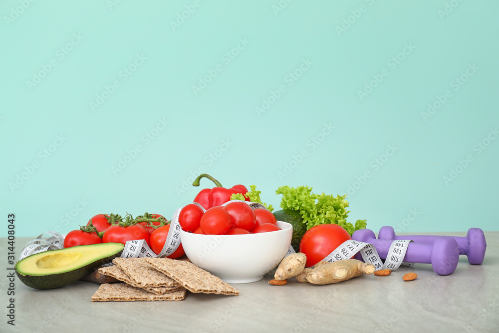 Different healthy food with measuring tape and dumbbells on table. Diet concept