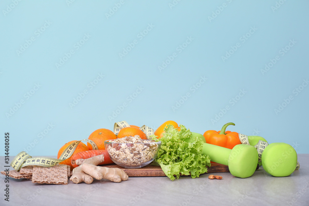 Different healthy food with measuring tape and dumbbells on table. Diet concept