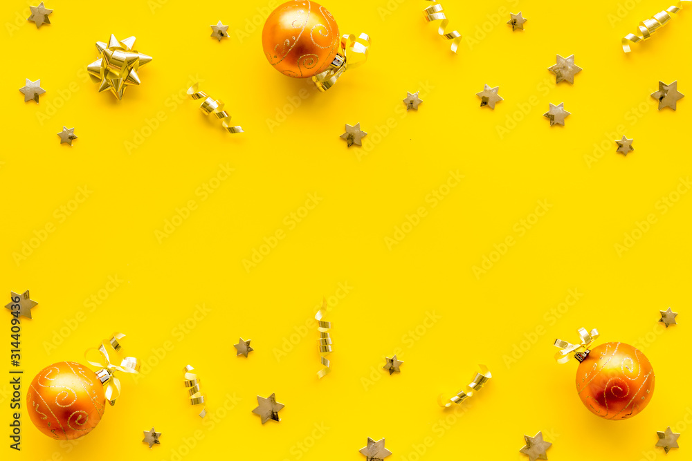 New Year decoration background - golden balls and bows on yellow desk top-down frame copy space