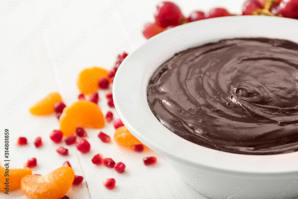 Bowl with tasty chocolate fondue and fruits on table, closeup