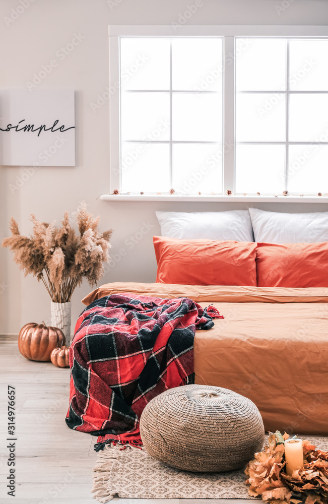 Stylish interior of room with big comfortable bed and autumn decor