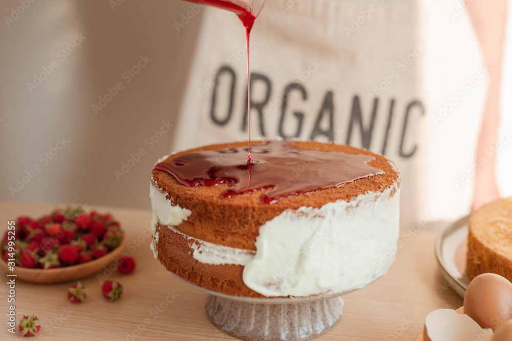 fresh sponge cake with raspberry syrup being poured over the top. Making red velvet or sponge cake p