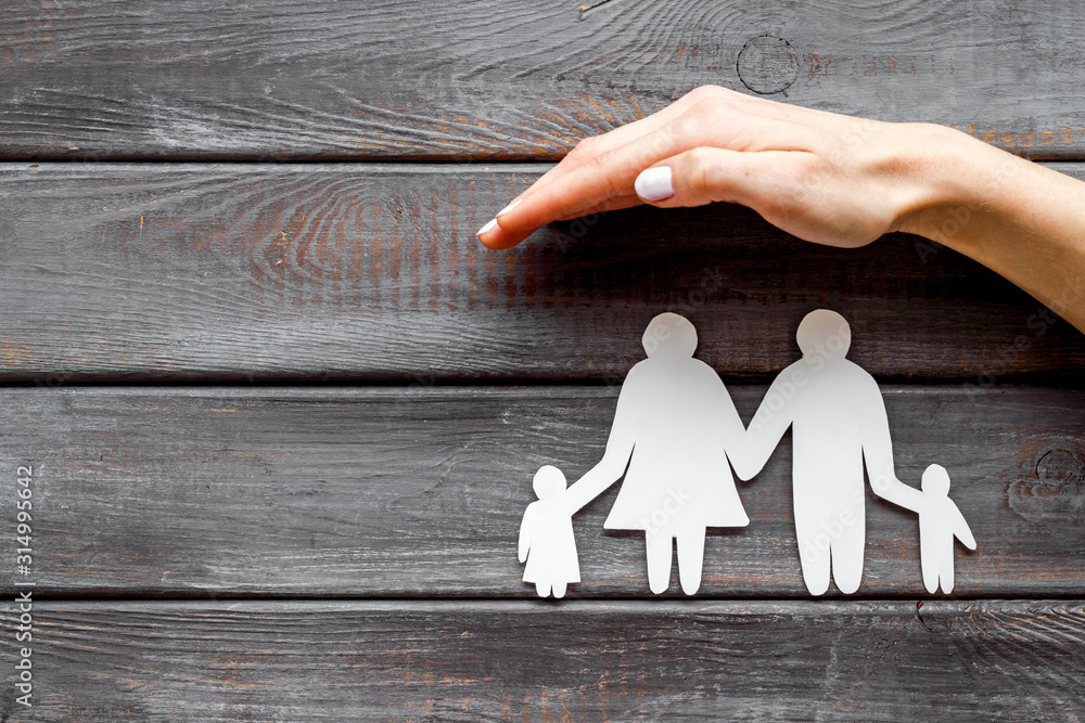 Live insurance concept. Family silhouette under palm on dark wooden background top-down copy space