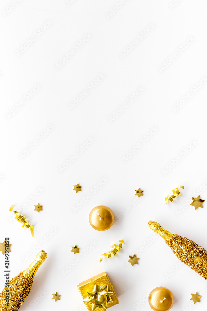 New Year background. Golden composition with champagne bottle and decorations on white desk top-down