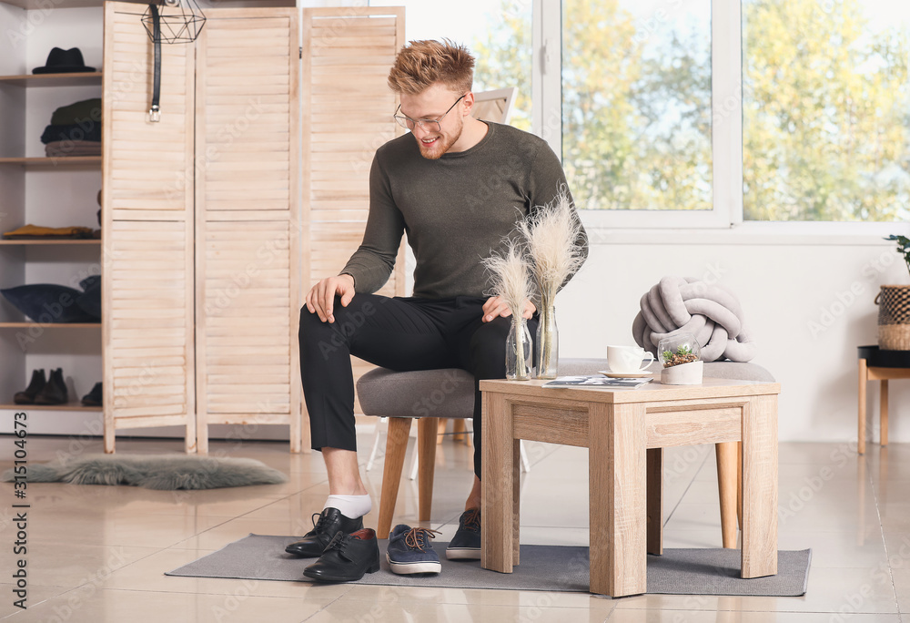 Handsome man putting on shoes in dressing room