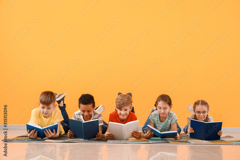 Cute little children reading books on color background